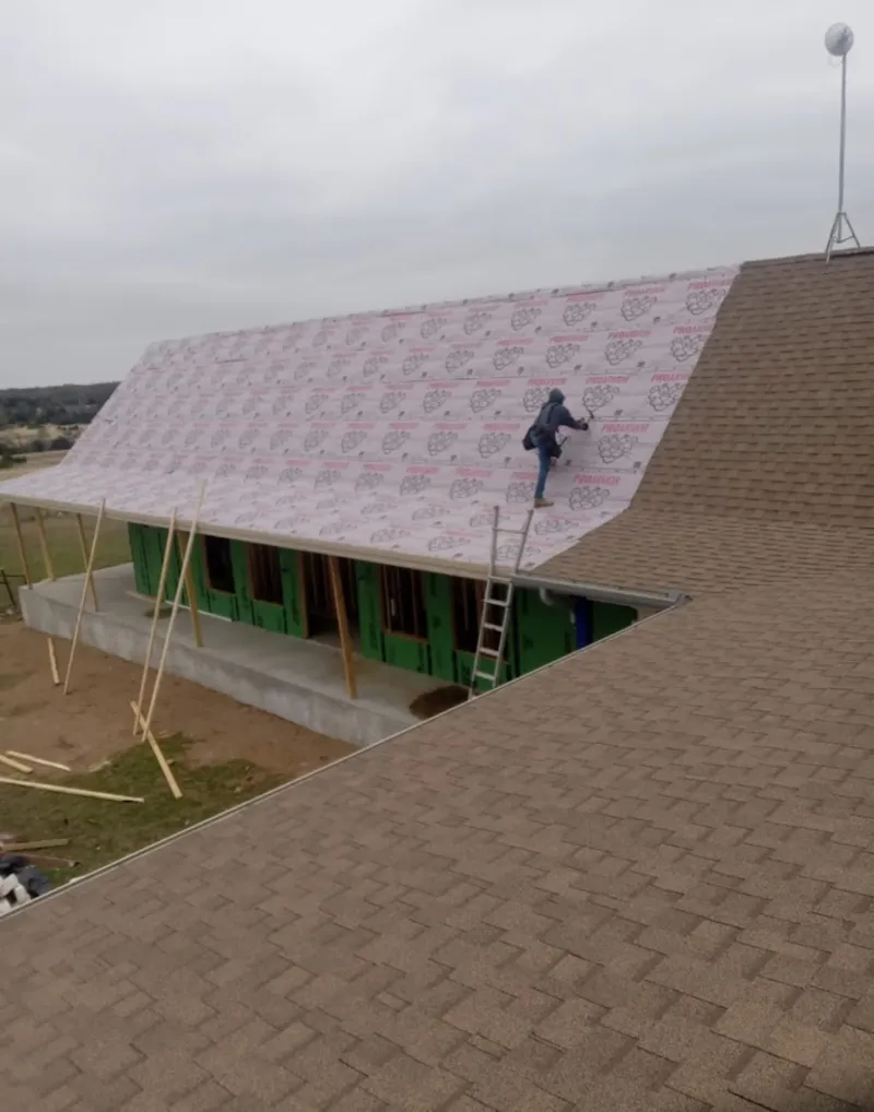Worker preparing underlayment for a metal roof installation in Kendallville